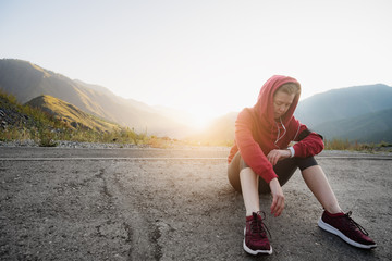 Sportswoman with smart watch taking a break outdoors at the top of the mountain.