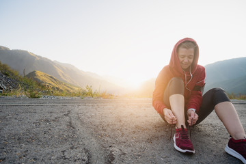 Sport runner woman tying laces before training. Marathon.