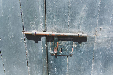 Rusty old slide bolt or tower bolt on a worn green door.