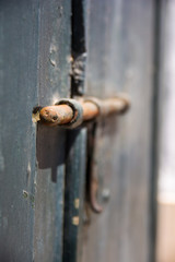 Rusty old slide bolt or tower bolt on a worn green door.
