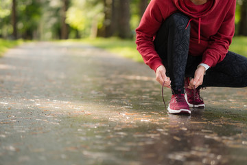 Tying sports shoe. Female athlete getting ready for athletic and fitness training outdoors.