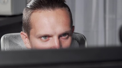 Sliding cropped shot of a male eyes looking at computer monitor. Unrecognizable man working online, using computer late at night. Technology, connection, internet using concept