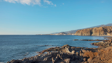 Volcanic rocky landscape of Malpais de la Rasca, a natural reserve close to Palm-Mar town, with views towards Atlantic Ocean and the tourist resort Los Cristianos, in Tenerife, Canary Islands, Spain 