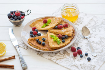  breakfast pancakes with blueberries raspberries and honey on a white table tea with lemon and cinnamon