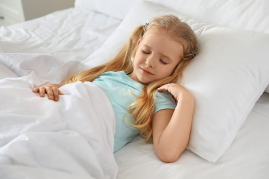 Portrait of cute little girl sleeping in large bed