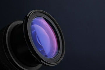 Lens of professional camera on dark blue background, closeup. Space for text