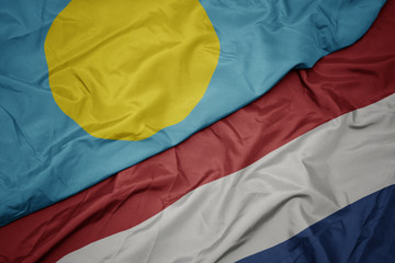 waving colorful flag of netherlands and national flag of Palau .