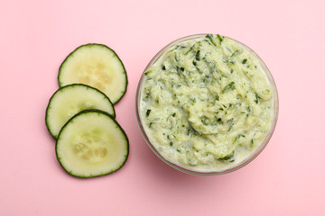 Handmade face mask and cucumber slices on pink background, flat lay