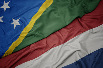 waving colorful flag of netherlands and national flag of Solomon Islands .