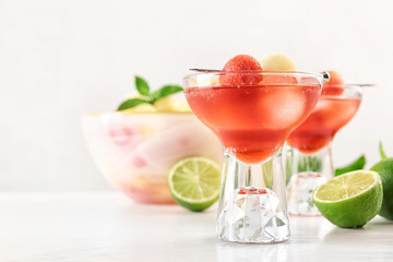 Glass of melon and watermelon ball cocktail on white wooden table. Space for text