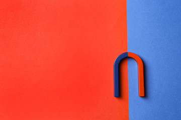 Red and blue horseshoe magnet on color background, top view. Space for text