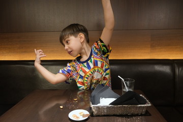 Fototapeta na wymiar Boy does a funny pose with a colourful shirt at a restaurant table with a glass, a bucket and a plate on the table in Tokyo