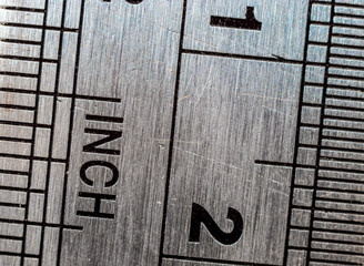 Macro close-up of a stainless steel ruler with british and metric system measuring scales: Inches...
