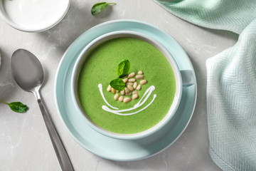 Cup of healthy green soup with fresh spinach served on light table, flat lay