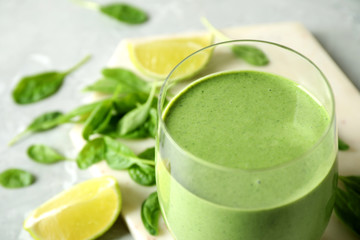 Glass of healthy green smoothie with fresh spinach on table, closeup
