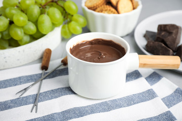 Fondue pot with chocolate and grape on table