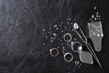 Flat lay composition with precious stones and jewelry tools on black leather background, space for...