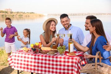 Happy families with little children having picnic at riverside