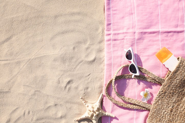 Flat lay composition with different beach accessories on sand. Space for text