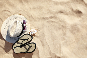 Flat lay composition with different beach accessories on sand. Space for text