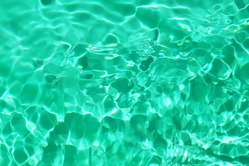 Abstract rippled water us textured  background neo mint color. Sun glare on the water