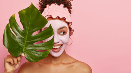 Cropped shot of happy young woman applies facial mud mask on face for removing wrinkless or fine...