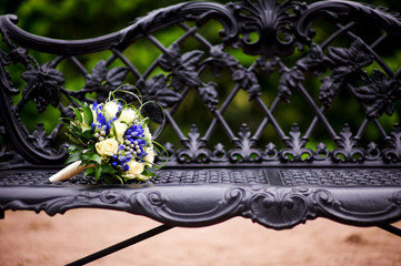 the bride s bouquet lies on the edge of an elegant cast-iron bench. Close up. Copy space
