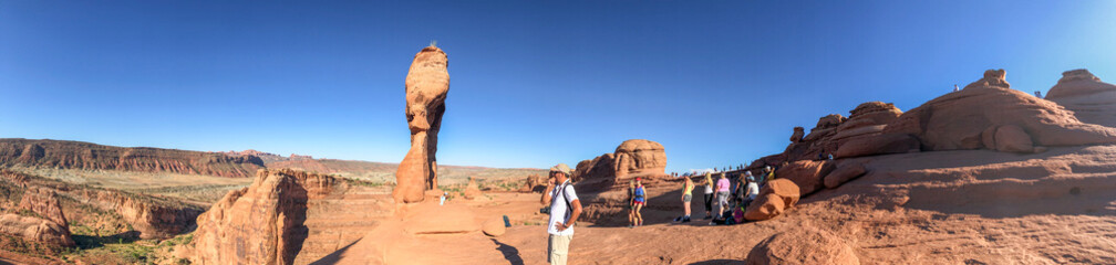ARCHES NATIONAL PARK, USA - JULY 2, 2019: Panoramic view of Delicate Arch and tourists