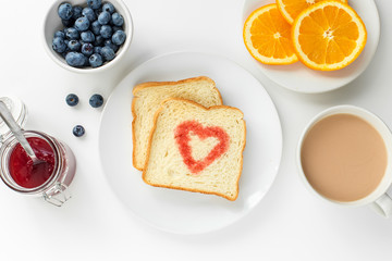 Breakfast with cup of tea, slice orange, toast heart of berry jam, blueberry