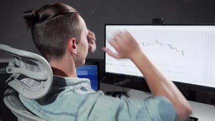 Rear view shot of a computer programmer stretching in his chair working late. Unrecognizable iT office worker stretching his back while working on his computer late at night