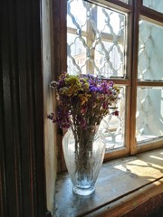 Kermek dried flowers autumn flowers in a glass vase against the background of an old tattered window
