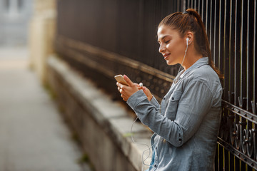 Beautiful Young Women Listening Music on her phone outdoors