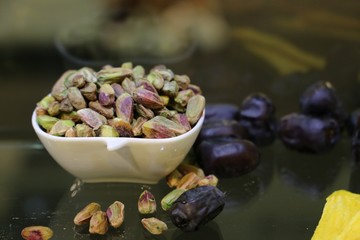 Pistachios in white porcelain bowls. Roasted pistachio seeds in shells and shelled