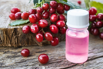 Tincture with viburnum, essential oil or an elixir with viburnum berries on a wooden table near a branch of red viburnum.