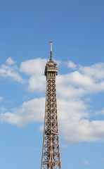 Fototapeta na wymiar Eiffel Tower Symbol of Paris with some white clouds in the blue