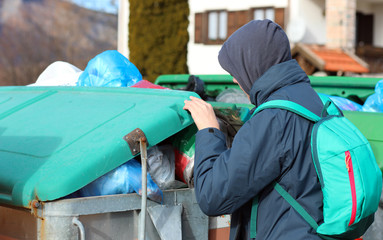 young gypsy looks for something to eat inside the bin
