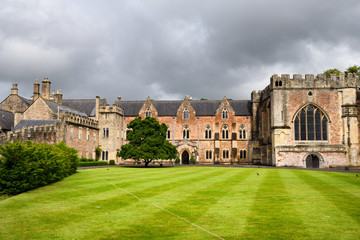 Bishop's Palace with Chapel and green Croquet Lawn under cloudy sky in Wells Somerset England