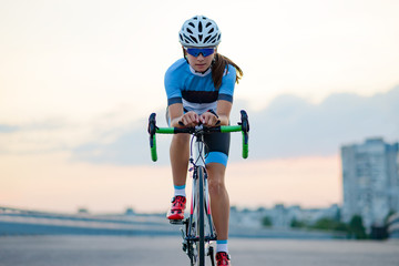 Young Woman Riding Road Bicycle on Free Street in the City at Sunset. Healthy Lifestyle and Sport Concept.
