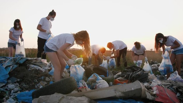 Group of eco volunteers cleaning up area of dump near the field during sunset, gimbal shot, slow mtoion