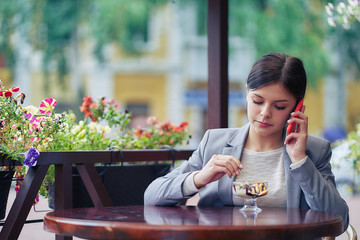 girl in a cafe eating ice cream and talking on the phone