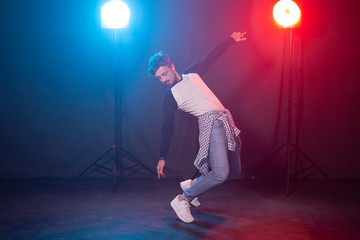 Fototapeta na wymiar Dance, hip-hop and reggaeton concept - young man dancing over the lights.