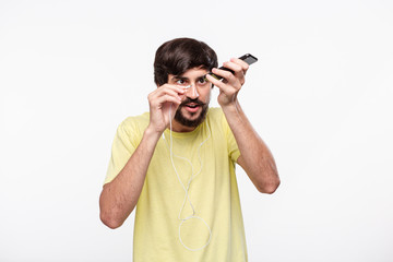 Handsome brunet bearded man with whiskers having problems connecting wired headphones into...
