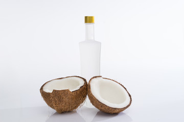 Coconut oil concept. Coconut with tall bottle isolated on white background.