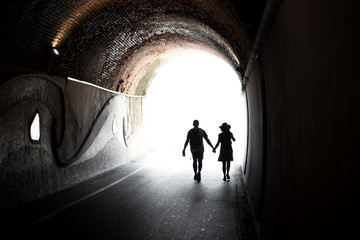 Couple walking hand in hand through a tunnel