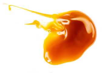 Melted caramel sauce isolated on a white background. Spilled maple syrup. Close up.