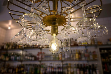 A Cocktail glasses hanging around the light bulb in the bar