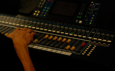 Hand of sound engineer on the control panel