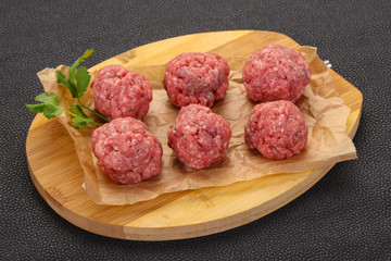 Raw meatball over wooden background