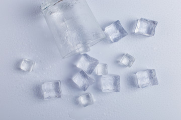 Empty inverted fallen glass with ice, on a white background.