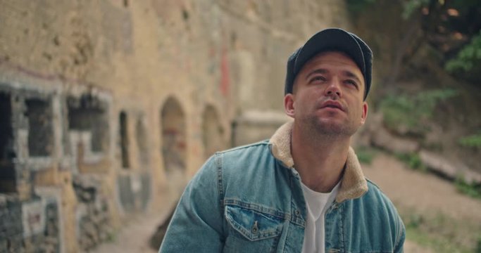 Handsome man in blue jeans jacket and white shirt, stylish hat looking around right and left . Peacky blinders. Waiting for something , Underground location, Camera rotation 